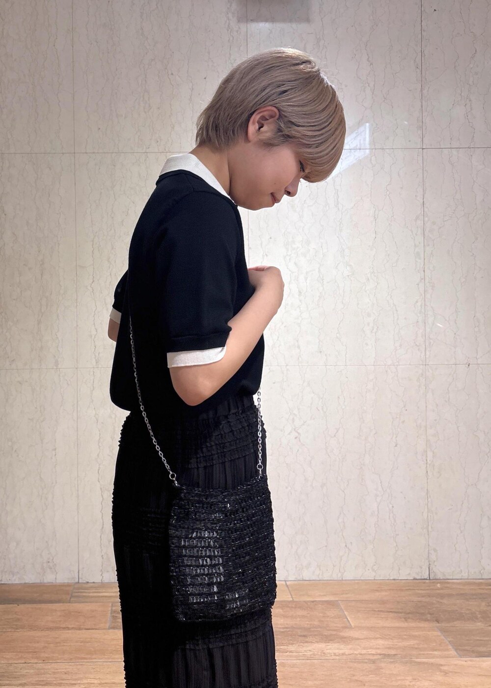 ブラック系のショルダーバッグ、グレー系のスカート、ブラック系のポロシャツを着用したレディースの春コーディネートの7枚目の写真