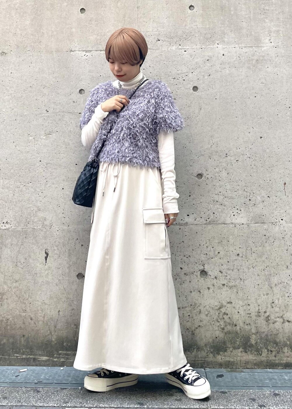 ホワイト系のTシャツ/カットソー、ベージュ系のスカート、ブラック系のスニーカーを着用したレディースの冬コーディネートの2枚目の写真