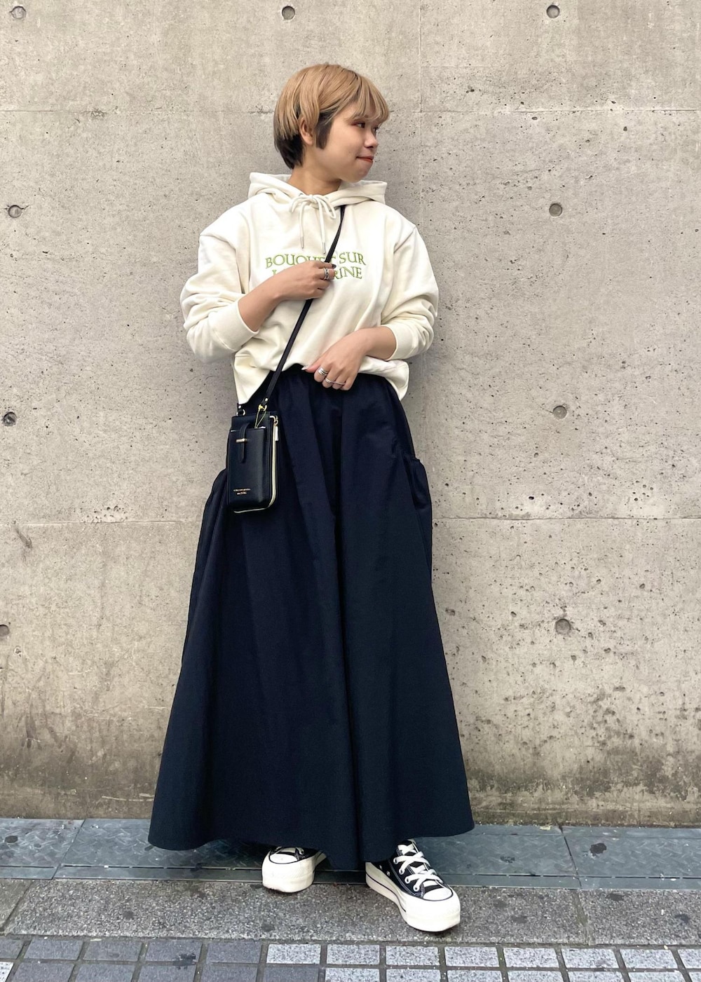 ブラック系のスニーカー、ブラック系のスカート、ブラック系のショルダーバッグを着用したレディースの春コーディネートの2枚目の写真