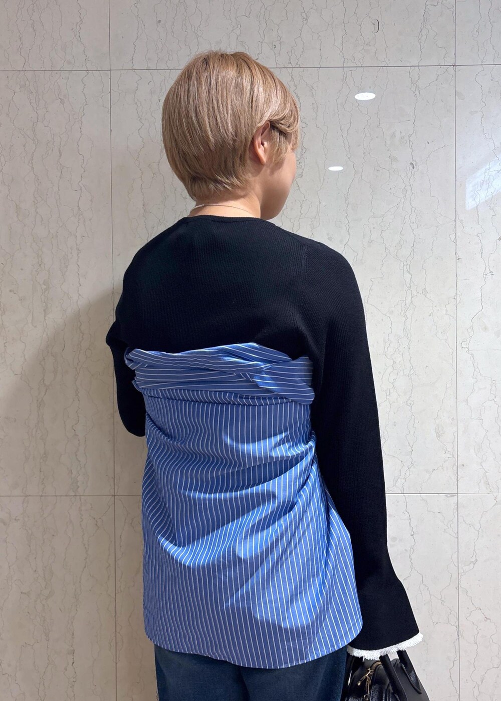 ブルー系のシャツ/ブラウス、ブラック系のニット/セーター、ブルー系のデニムパンツを着用したレディースの春コーディネートの5枚目の写真