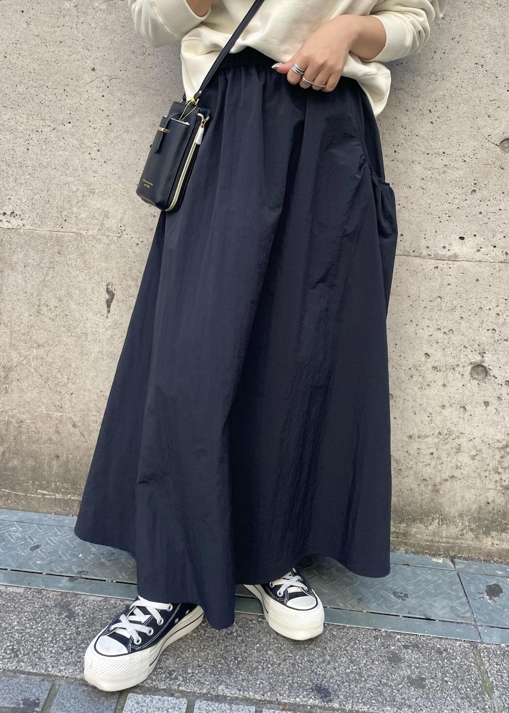 ブラック系のスニーカー、ブラック系のスカート、ブラック系のショルダーバッグを着用したレディースの春コーディネートの6枚目の写真