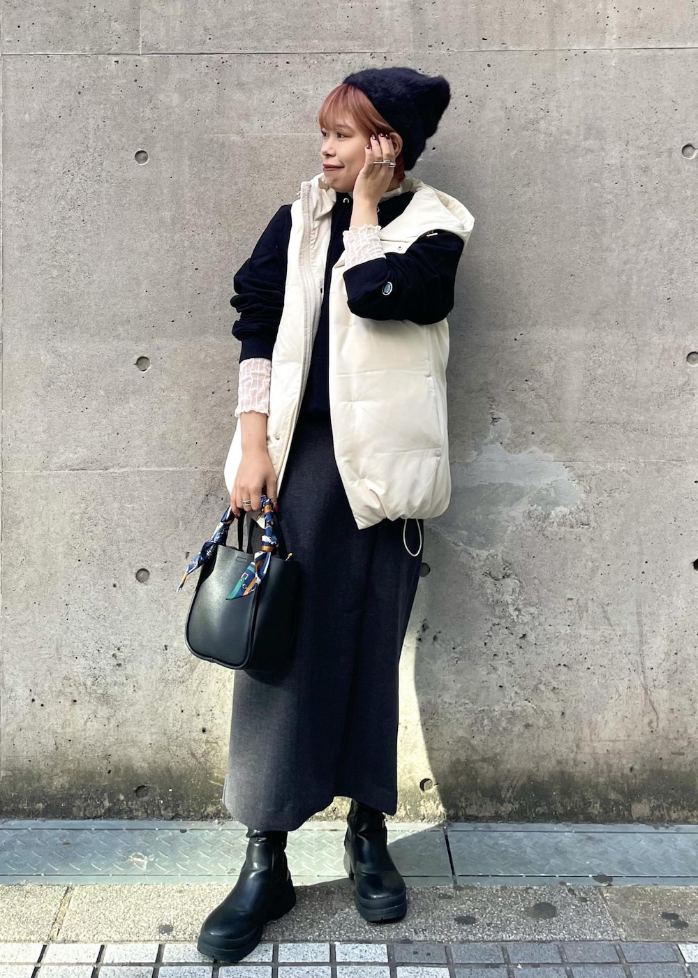 ホワイト系のTシャツ/カットソー、ホワイト系のダウンベスト、グレー系のスカートを着用したレディースの冬コーディネートの2枚目の写真