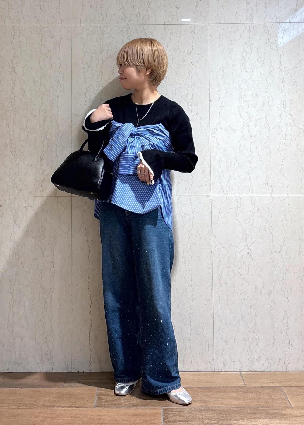 ブルー系のシャツ/ブラウス、ブラック系のニット/セーター、ブルー系のデニムパンツを着用したレディースの春コーディネートの2枚目の写真