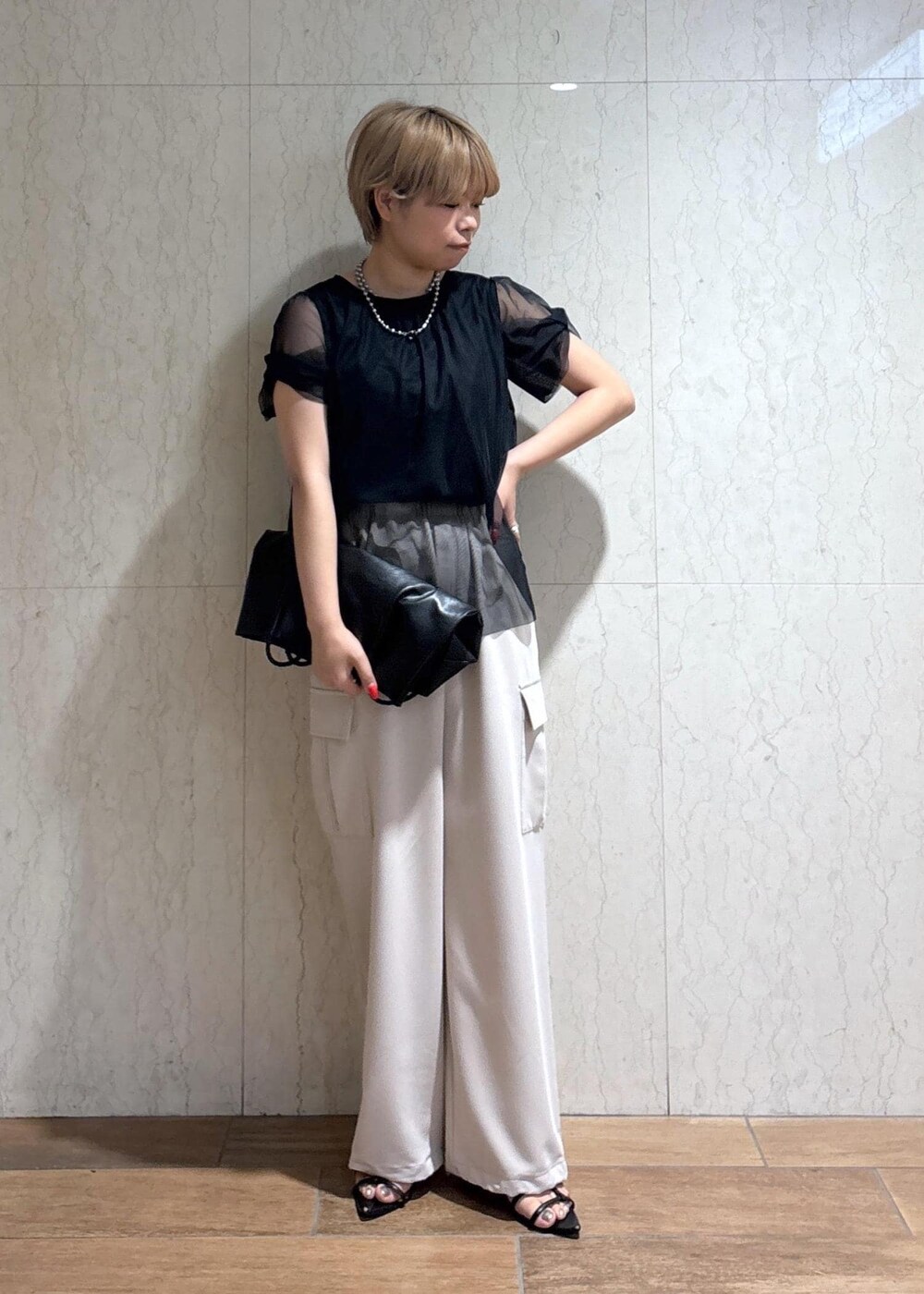 ブラック系のトートバッグ、ベージュ系のカーゴパンツ、ブラック系のTシャツ/カットソーを着用したレディースの春コーディネートの2枚目の写真