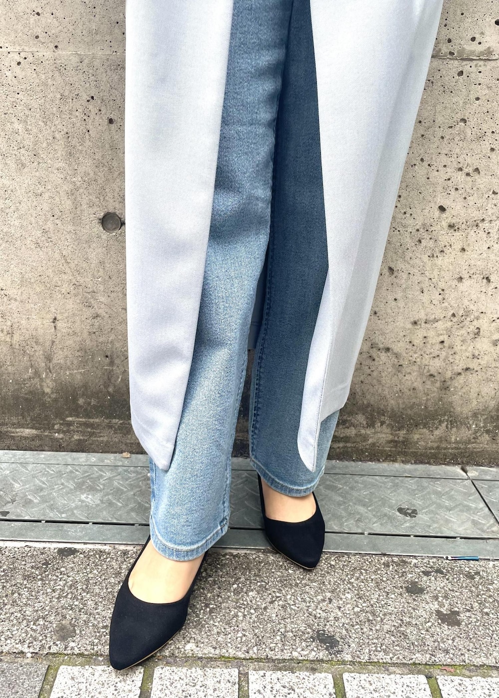 ブラック系のパンプス、ブラック系のショルダーバッグ、ブルー系のジャンパースカートを着用したレディースの春コーディネートの6枚目の写真