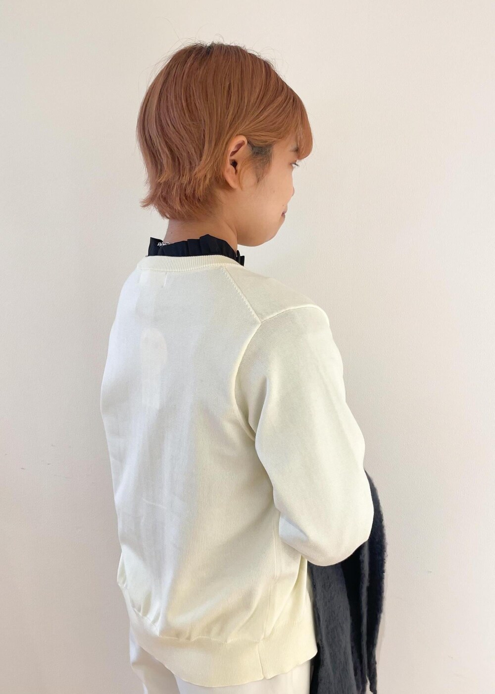 ホワイト系のカーディガン/ボレロ、ブラック系のパンプス、グレー系のシャツ/ブラウスを着用したレディースの冬コーディネートの5枚目の写真