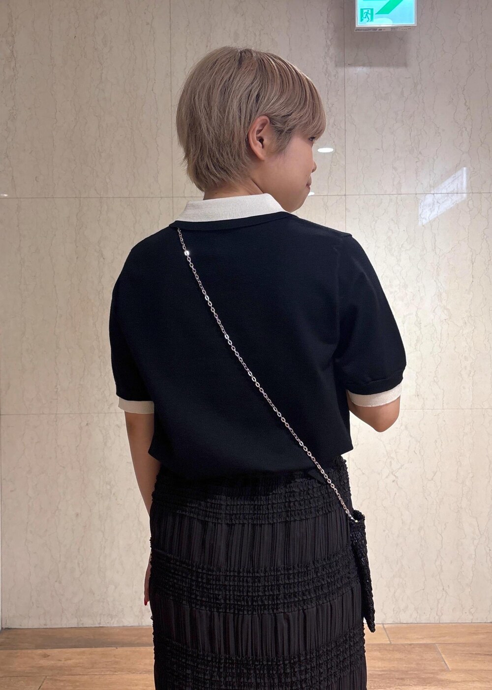 ブラック系のショルダーバッグ、グレー系のスカート、ブラック系のポロシャツを着用したレディースの春コーディネートの8枚目の写真