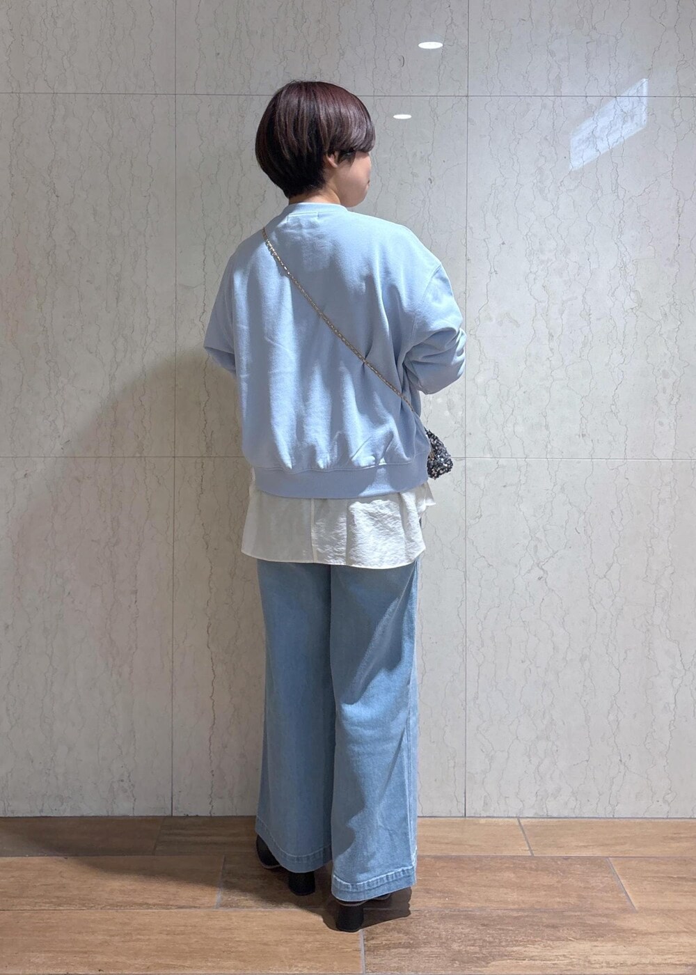 ブルー系のデニムパンツ、ブラック系のブーツ、グレー系のショルダーバッグを着用したレディースの冬コーディネートの3枚目の写真