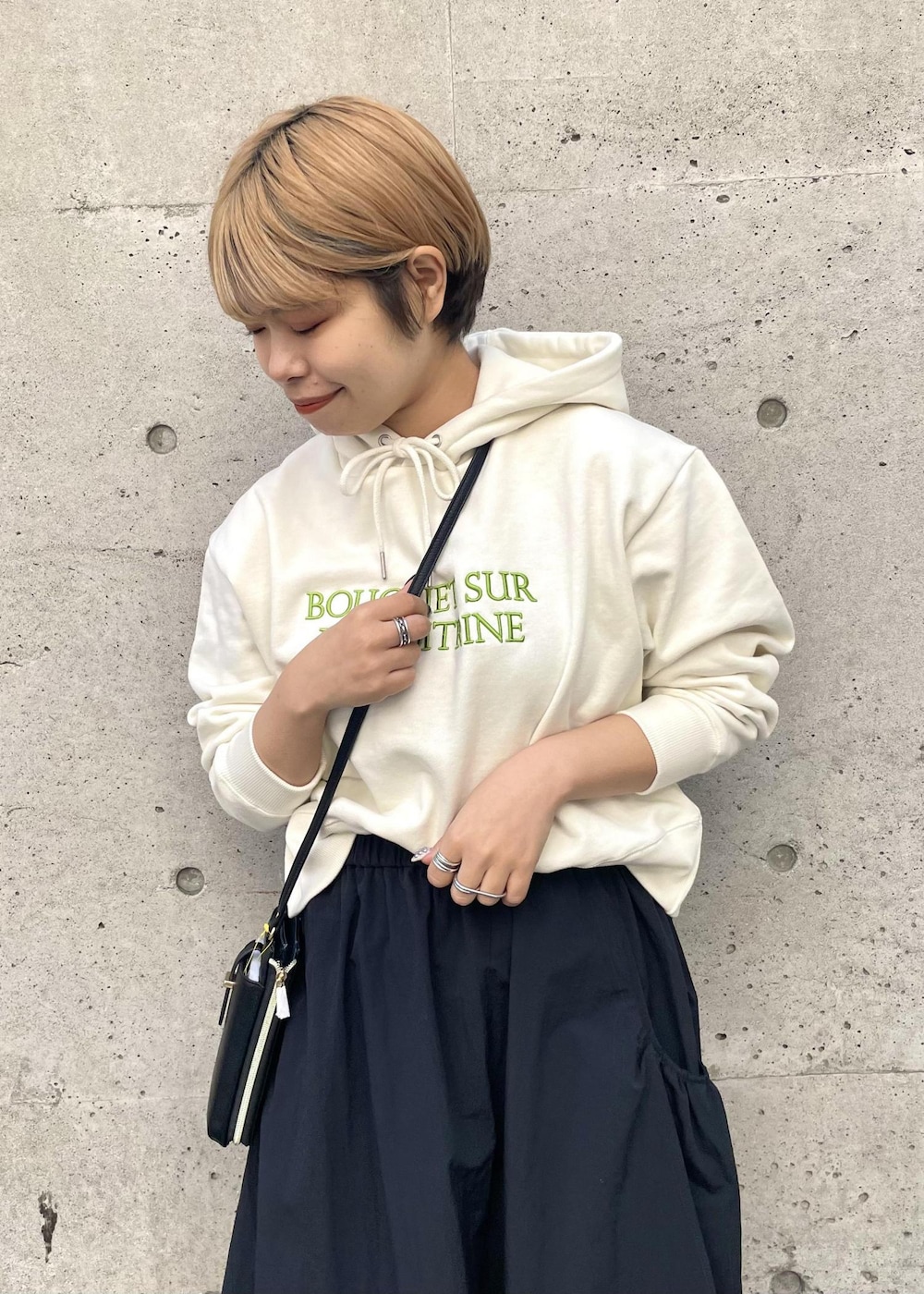 ブラック系のスニーカー、ブラック系のスカート、ブラック系のショルダーバッグを着用したレディースの春コーディネートの4枚目の写真