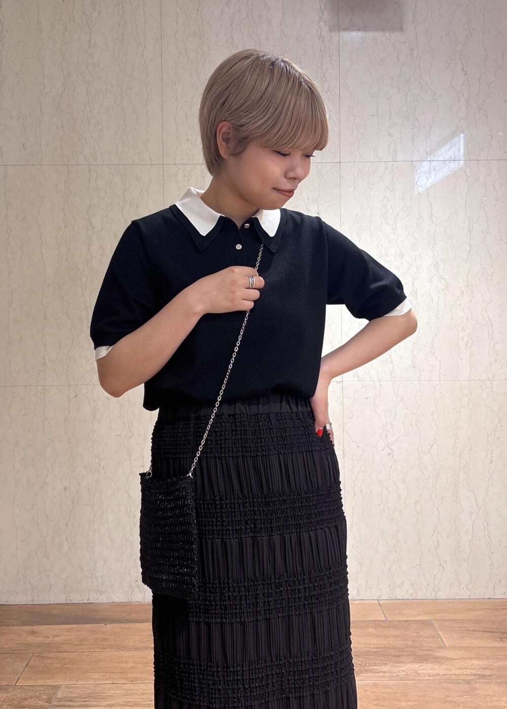 ブラック系のショルダーバッグ、グレー系のスカート、ブラック系のポロシャツを着用したレディースの春コーディネートの6枚目の写真