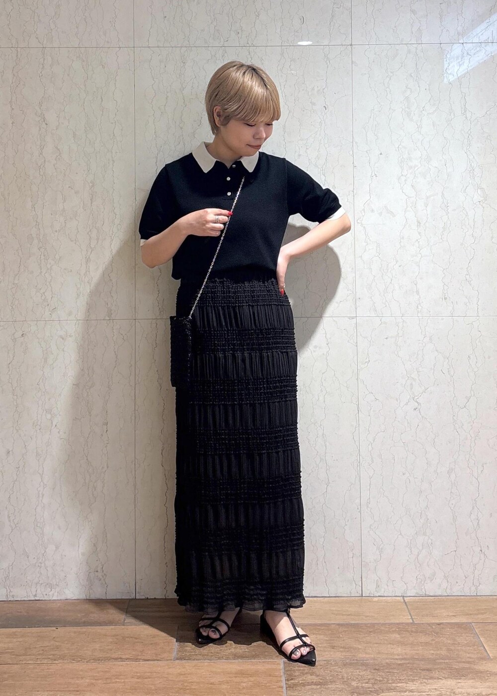 ブラック系のショルダーバッグ、グレー系のスカート、ブラック系のポロシャツを着用したレディースの春コーディネートの3枚目の写真