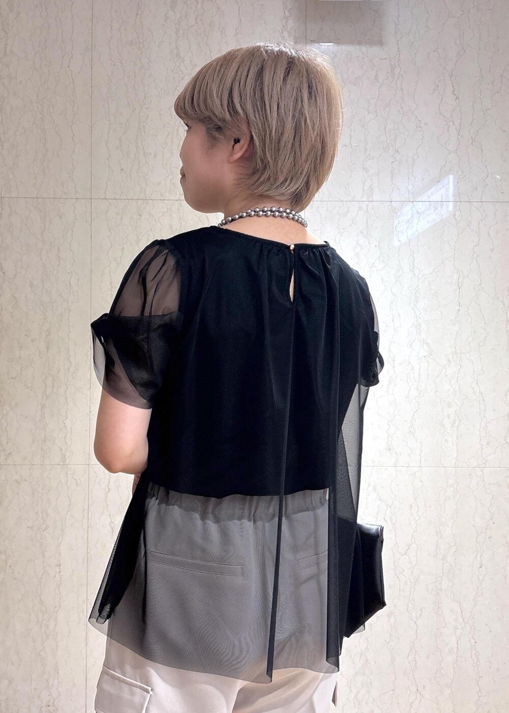 ブラック系のトートバッグ、ベージュ系のカーゴパンツ、ブラック系のTシャツ/カットソーを着用したレディースの春コーディネートの7枚目の写真