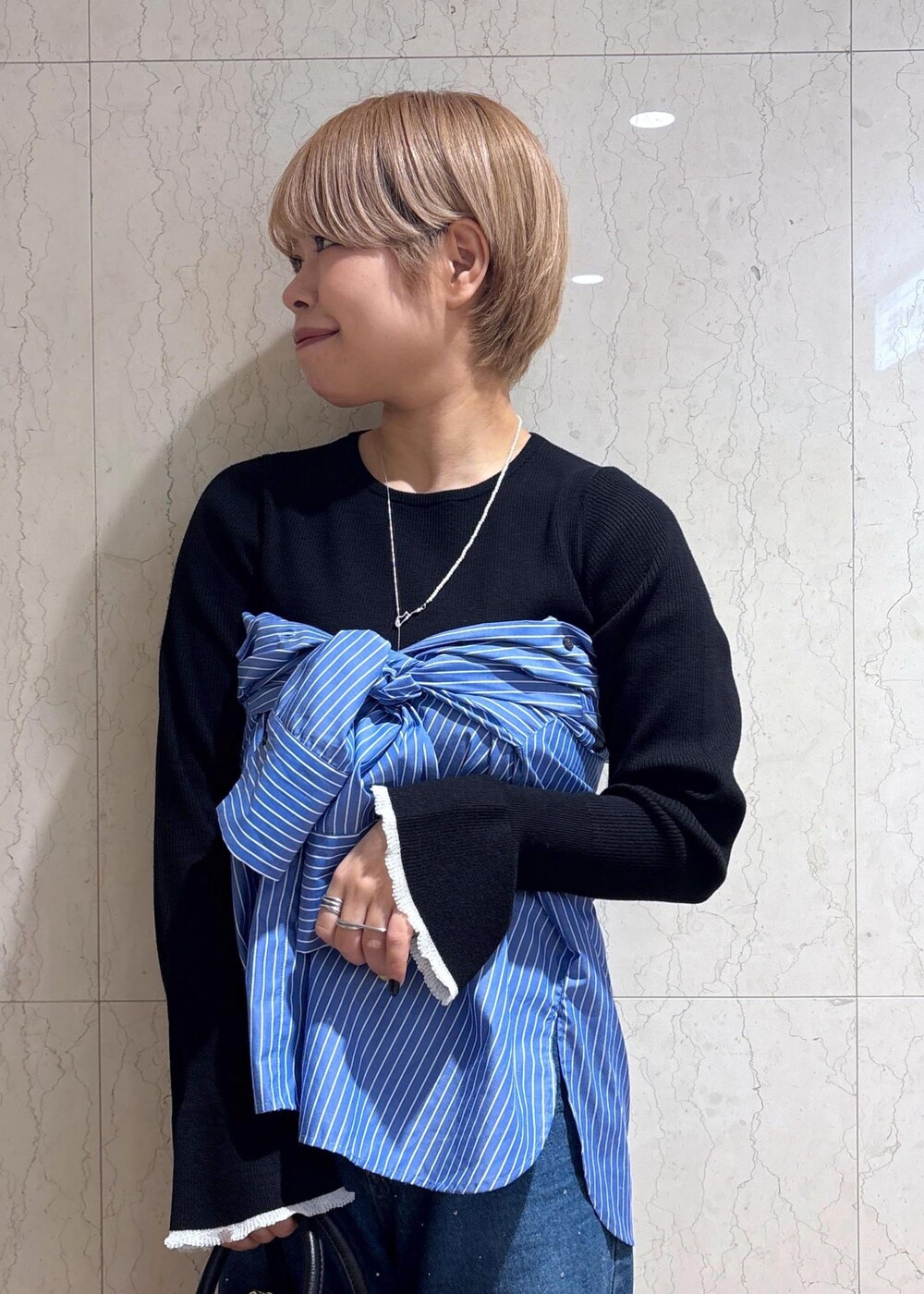 ブルー系のシャツ/ブラウス、ブラック系のニット/セーター、ブルー系のデニムパンツを着用したレディースの春コーディネートの3枚目の写真