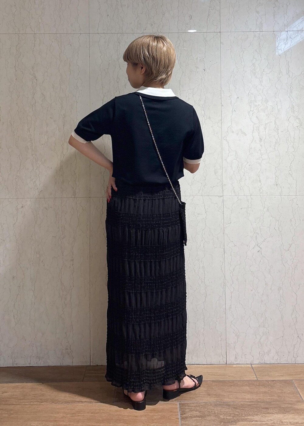 ブラック系のショルダーバッグ、グレー系のスカート、ブラック系のポロシャツを着用したレディースの春コーディネートの5枚目の写真