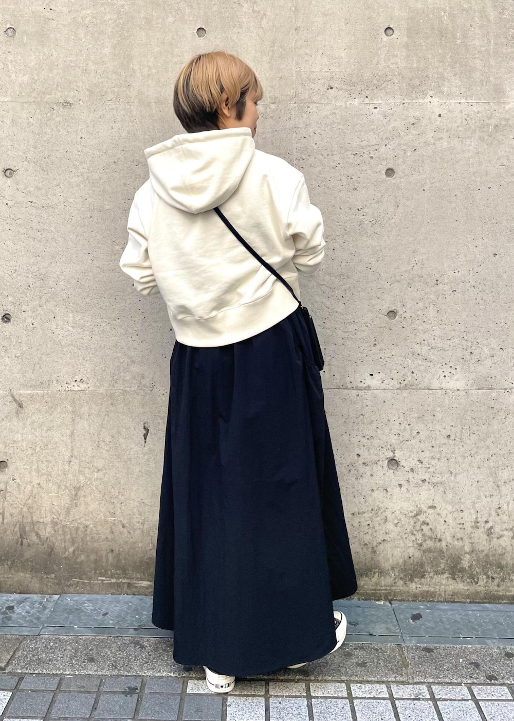 ブラック系のスニーカー、ブラック系のスカート、ブラック系のショルダーバッグを着用したレディースの春コーディネートの3枚目の写真