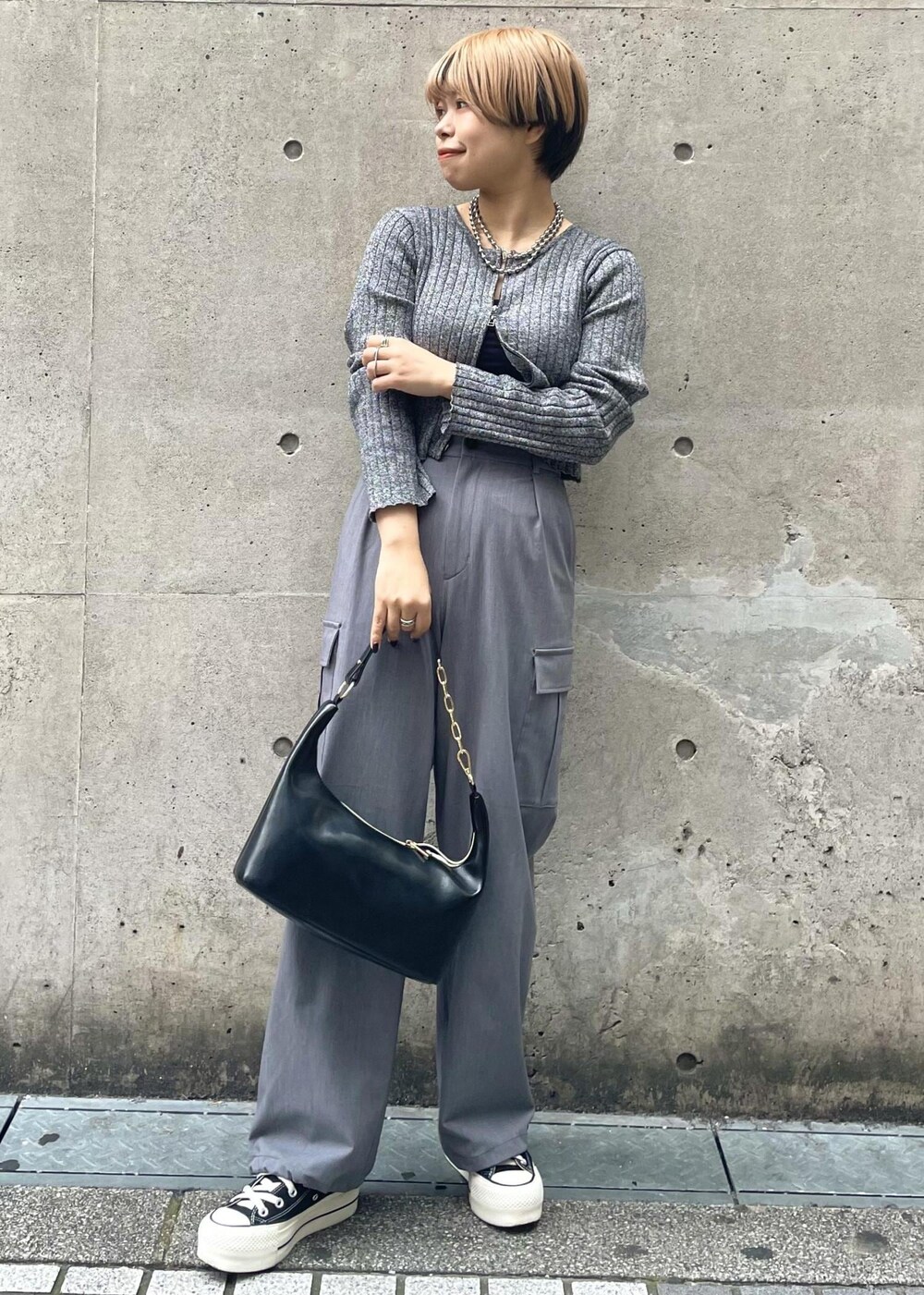 ブラック系のスニーカー、グレー系のカーゴパンツ、ブラック系のニット/セーターを着用したレディースの冬コーディネートの2枚目の写真