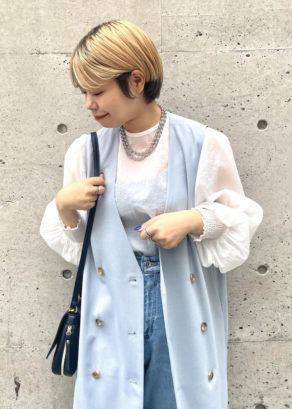 ブラック系のパンプス、ブラック系のショルダーバッグ、ブルー系のジャンパースカートを着用したレディースの春コーディネートの3枚目の写真