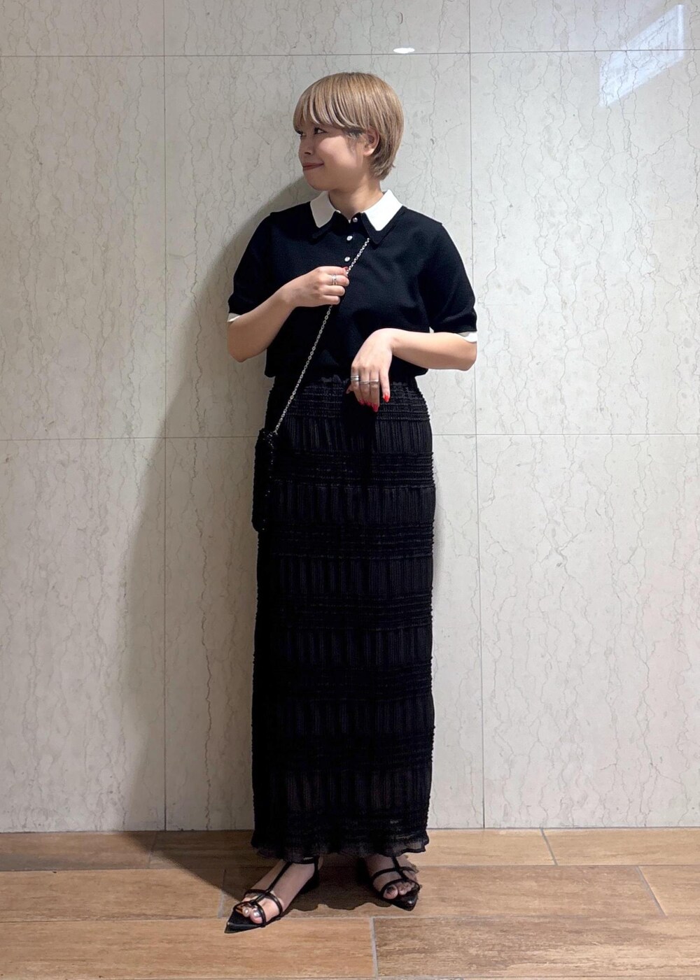 ブラック系のショルダーバッグ、グレー系のスカート、ブラック系のポロシャツを着用したレディースの春コーディネートの2枚目の写真