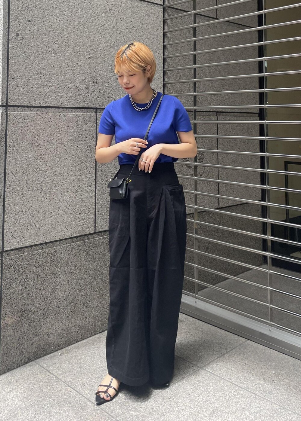 ブラック系のその他パンツ、ブラック系のショルダーバッグ、ブルー系のニット/セーターを着用したレディースの夏コーディネートの2枚目の写真