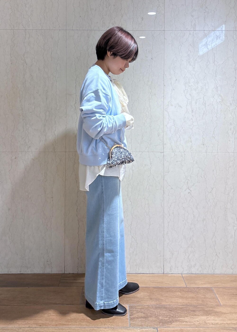 ブルー系のデニムパンツ、ブラック系のブーツ、グレー系のショルダーバッグを着用したレディースの冬コーディネートの4枚目の写真