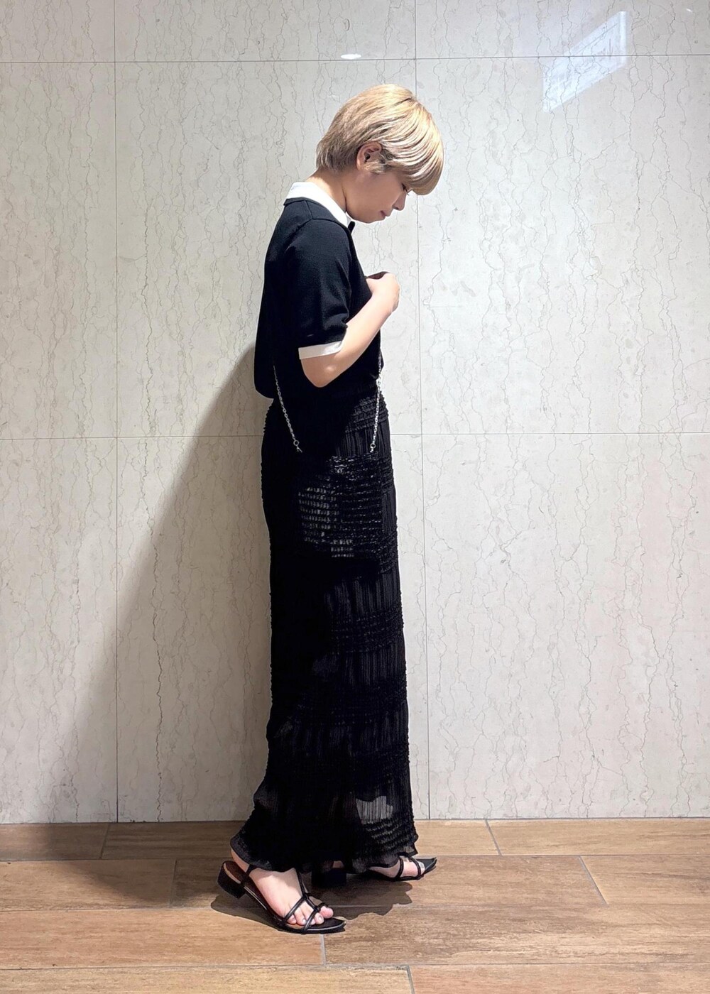 ブラック系のショルダーバッグ、グレー系のスカート、ブラック系のポロシャツを着用したレディースの春コーディネートの4枚目の写真