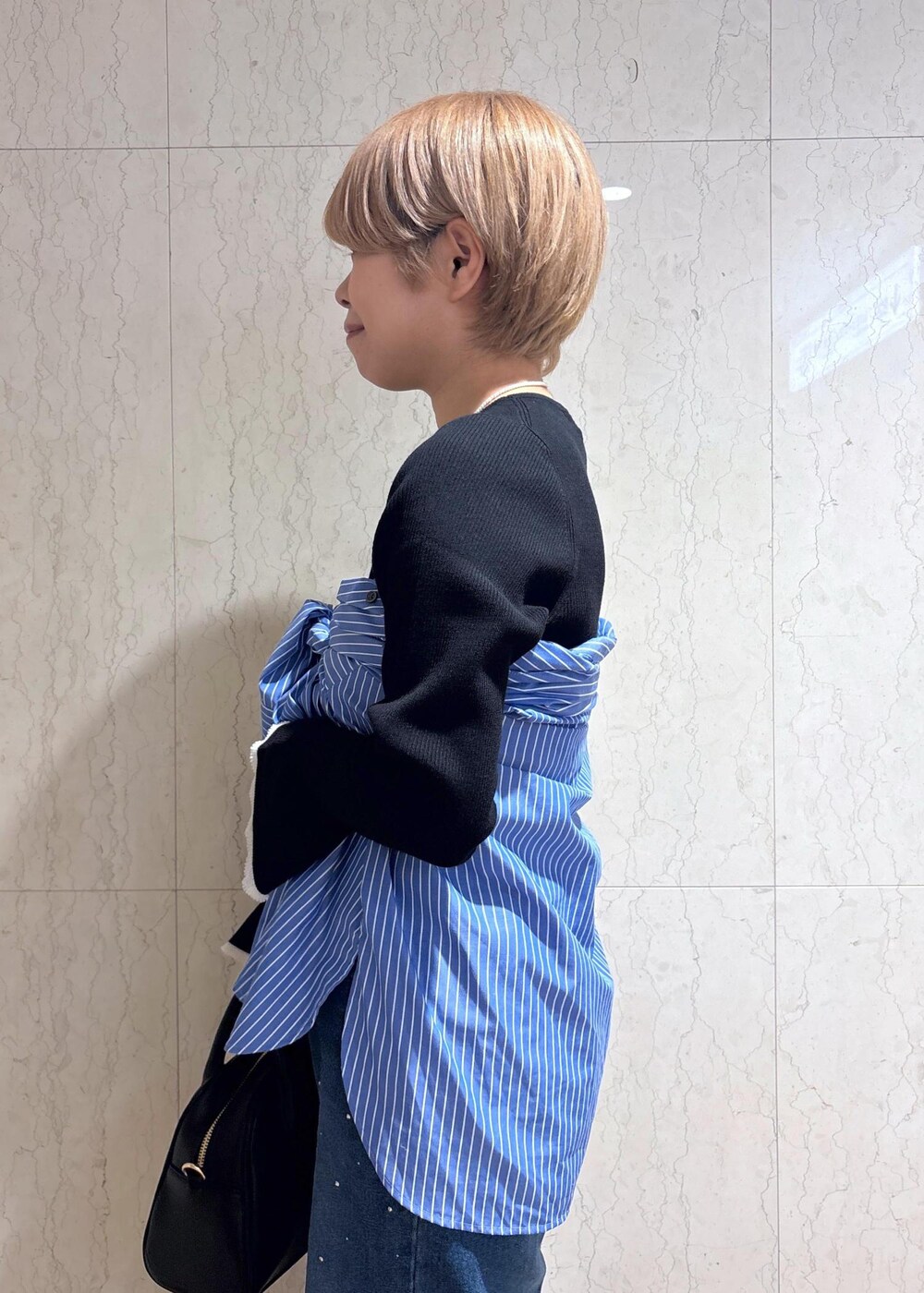 ブルー系のシャツ/ブラウス、ブラック系のニット/セーター、ブルー系のデニムパンツを着用したレディースの春コーディネートの4枚目の写真