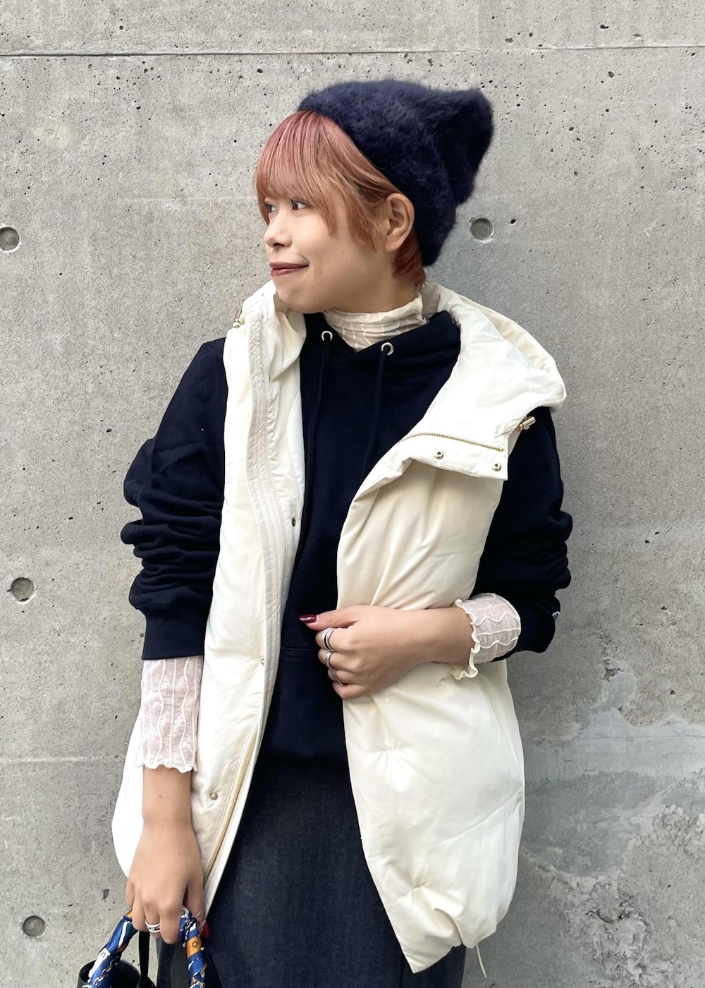 ホワイト系のTシャツ/カットソー、ホワイト系のダウンベスト、グレー系のスカートを着用したレディースの冬コーディネートの4枚目の写真