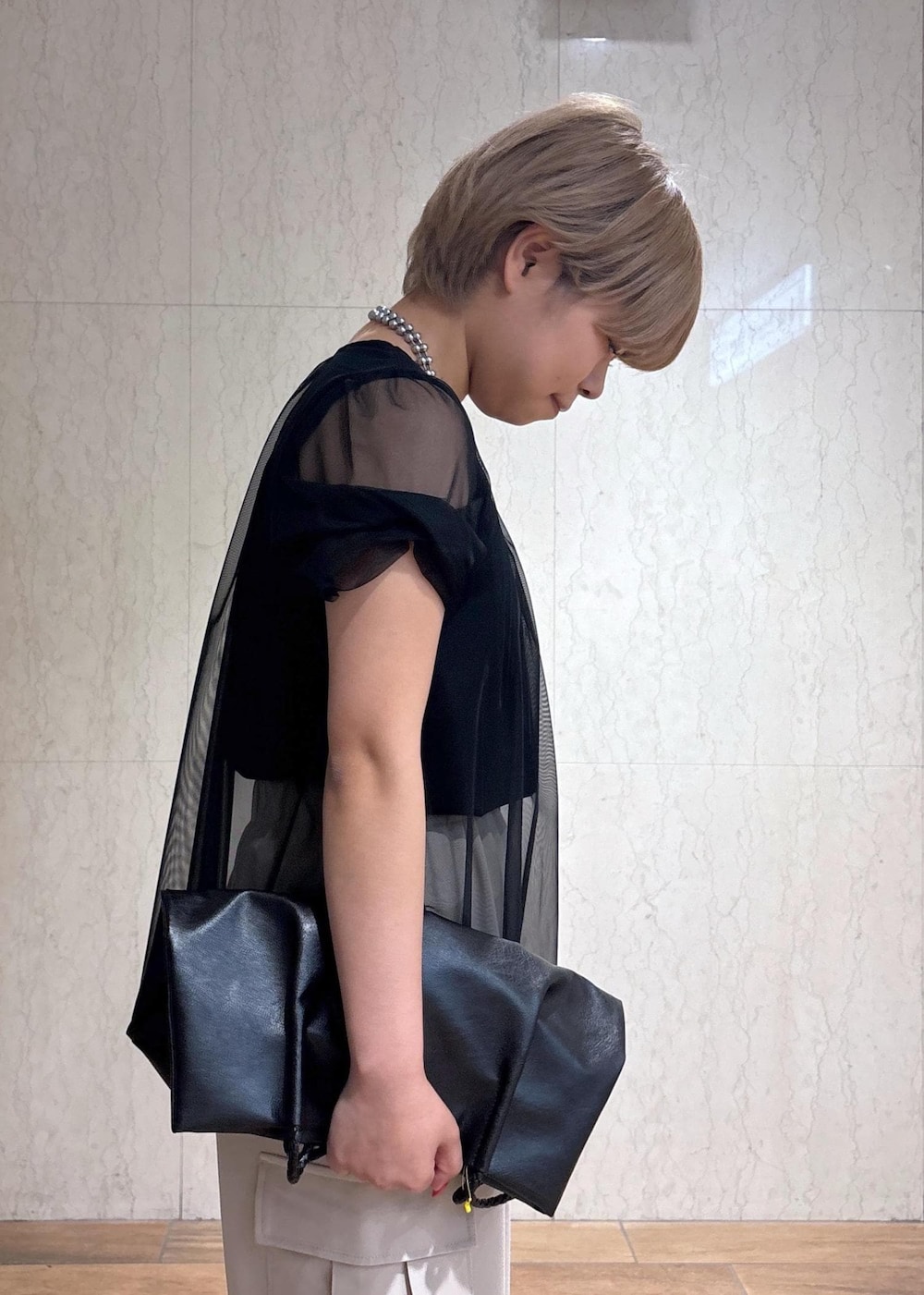 ブラック系のトートバッグ、ベージュ系のカーゴパンツ、ブラック系のTシャツ/カットソーを着用したレディースの春コーディネートの6枚目の写真