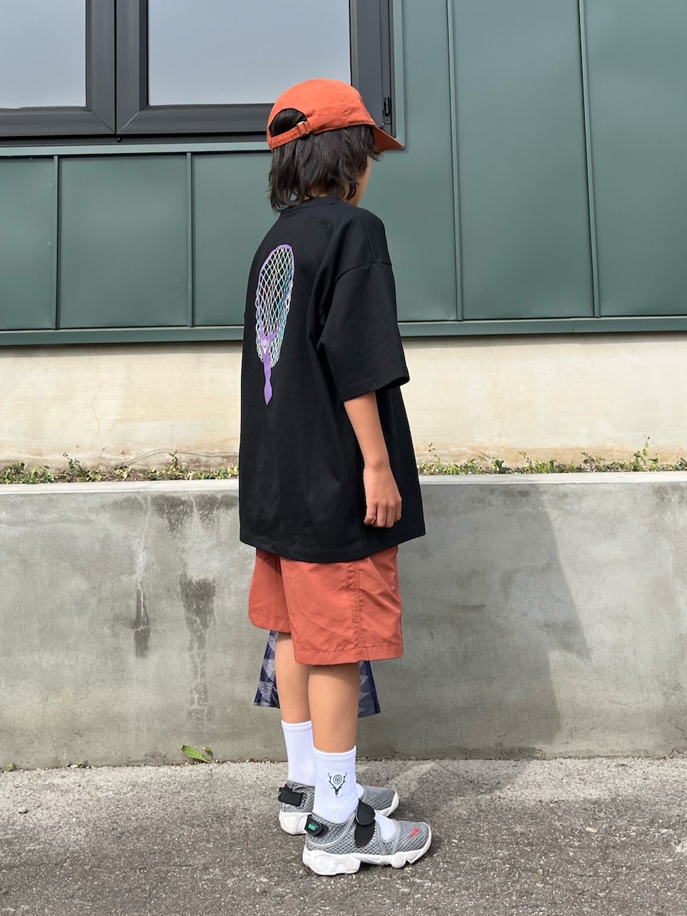 ブラック系のTシャツ/カットソー、オレンジ系のパンツ、パープル系のハンドバッグを着用したキッズの夏コーディネートの2枚目の写真