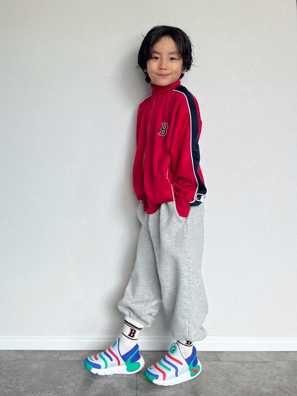 レッド系のジャージ、グレー系のスウェットパンツ、グレー系のスリッポンを着用したキッズの春コーディネートの3枚目の写真