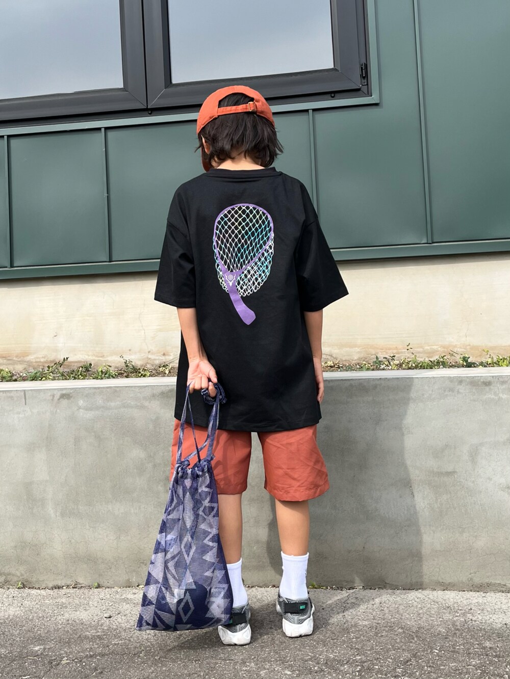 ブラック系のTシャツ/カットソー、オレンジ系のパンツ、パープル系のハンドバッグを着用したキッズの夏コーディネートの3枚目の写真