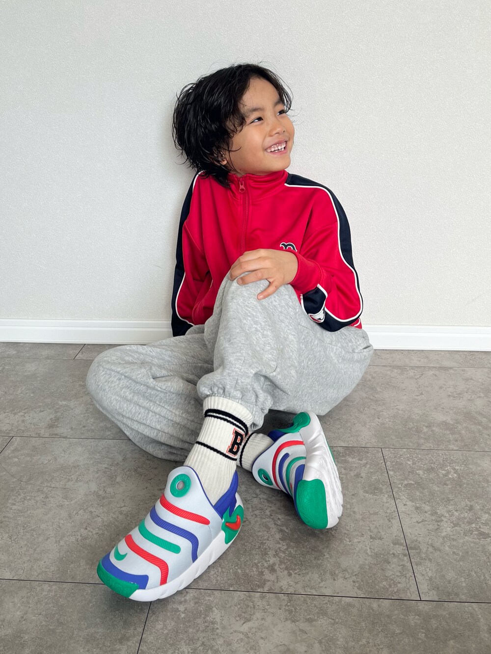 レッド系のジャージ、グレー系のスウェットパンツ、グレー系のスリッポンを着用したキッズの春コーディネートの2枚目の写真