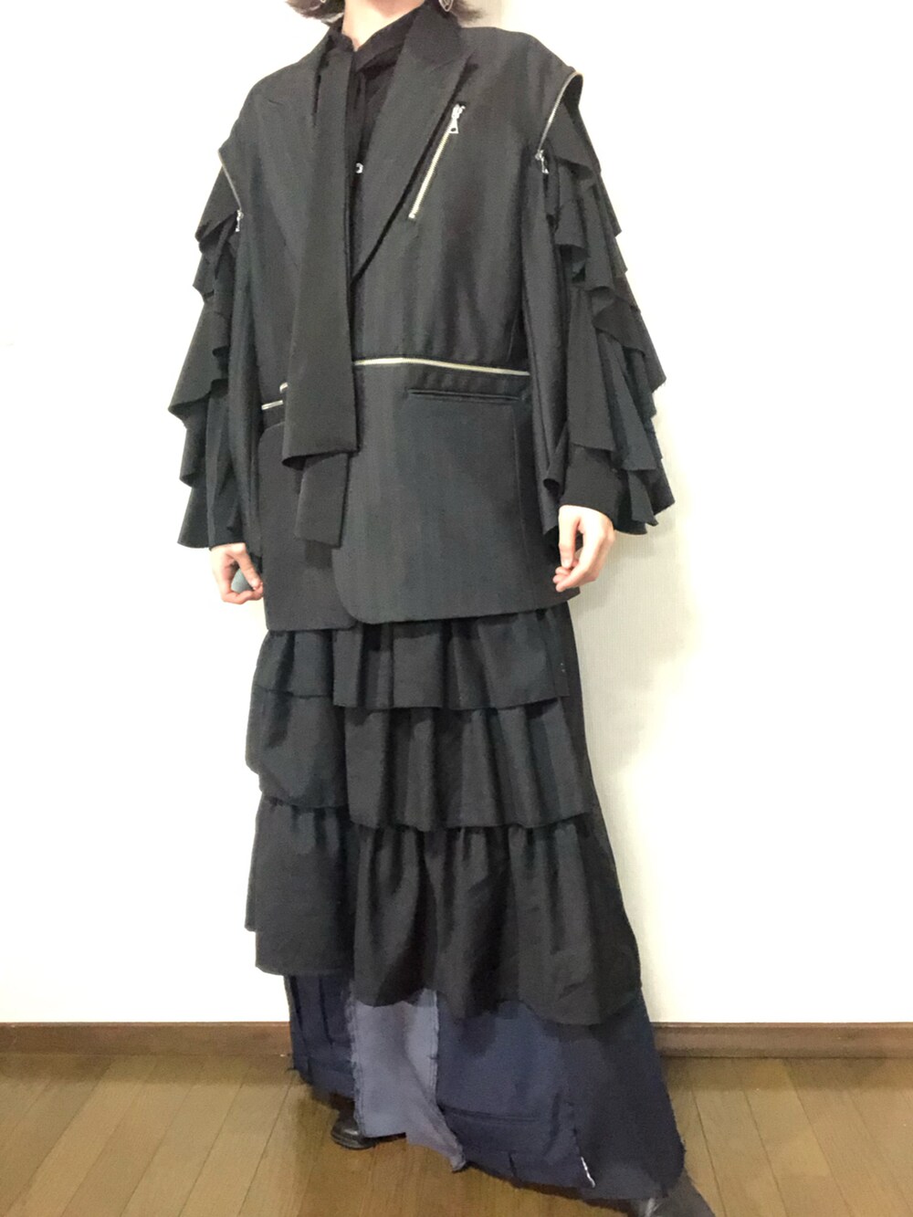 グレー系のテーラードジャケット、ブラック系のスカート、ブラック系のパンツを着用したメンズの春コーディネートの3枚目の写真