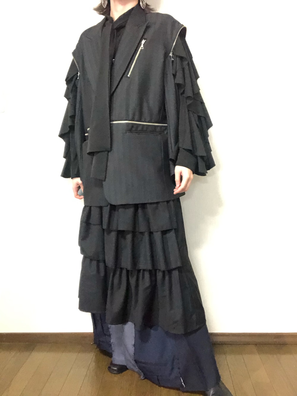 グレー系のテーラードジャケット、ブラック系のスカート、ブラック系のパンツを着用したメンズの春コーディネートの2枚目の写真