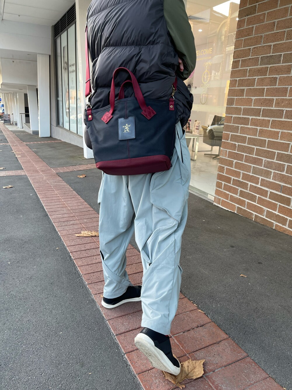 グレー系のダウンベスト、ホワイト系のチノパンツ、ブラック系のスリッポンを着用したメンズの春コーディネートの3枚目の写真