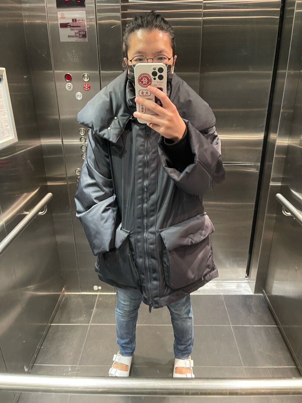 ブラック系のダウンベスト、ブルー系のデニムパンツ、ブラック系のサンダルを着用したメンズの春コーディネートの2枚目の写真