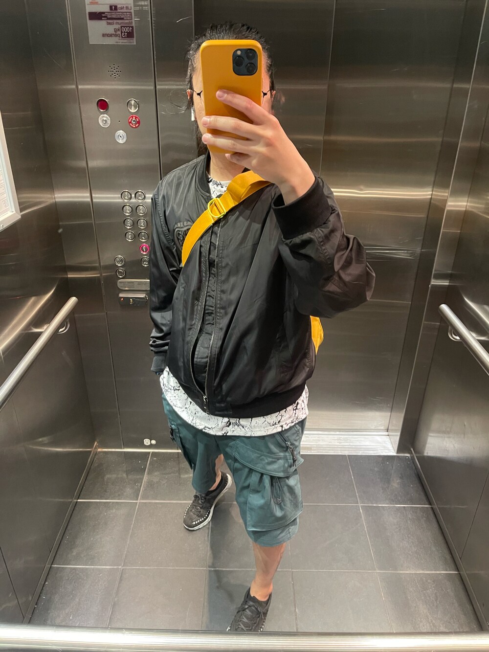 グリーン系のカーゴパンツ、ブラック系のノーカラージャケットを着用したメンズの春コーディネートの2枚目の写真