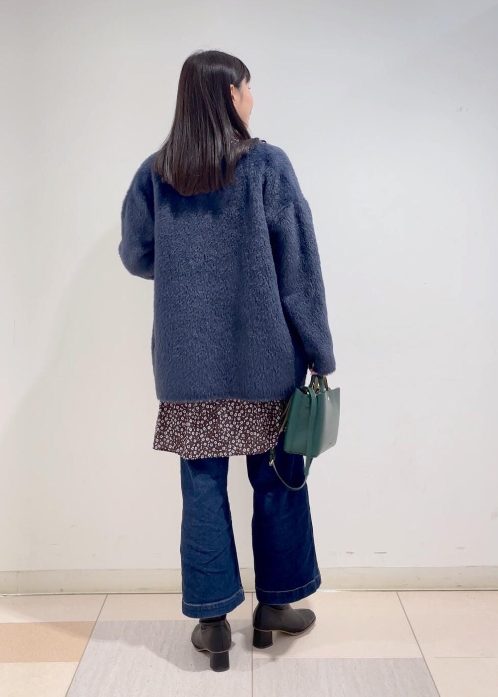 ブルー系のデニムパンツ、ブラウン系のワンピース、ブラック系のブーツを着用したレディースの冬コーディネートの3枚目の写真