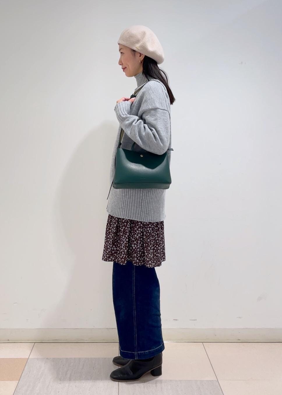 ブルー系のデニムパンツ、グレー系のニット/セーター、ブラウン系のワンピースを着用したレディースの冬コーディネートの2枚目の写真
