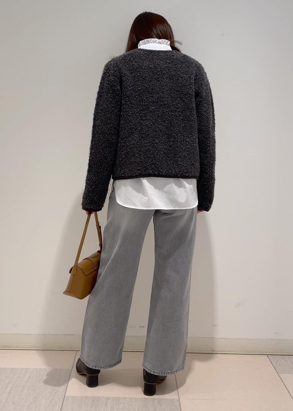 ブラウン系のショルダーバッグ、ブラック系のブーツ、グレー系のブルゾンを着用したレディースの冬コーディネートの5枚目の写真