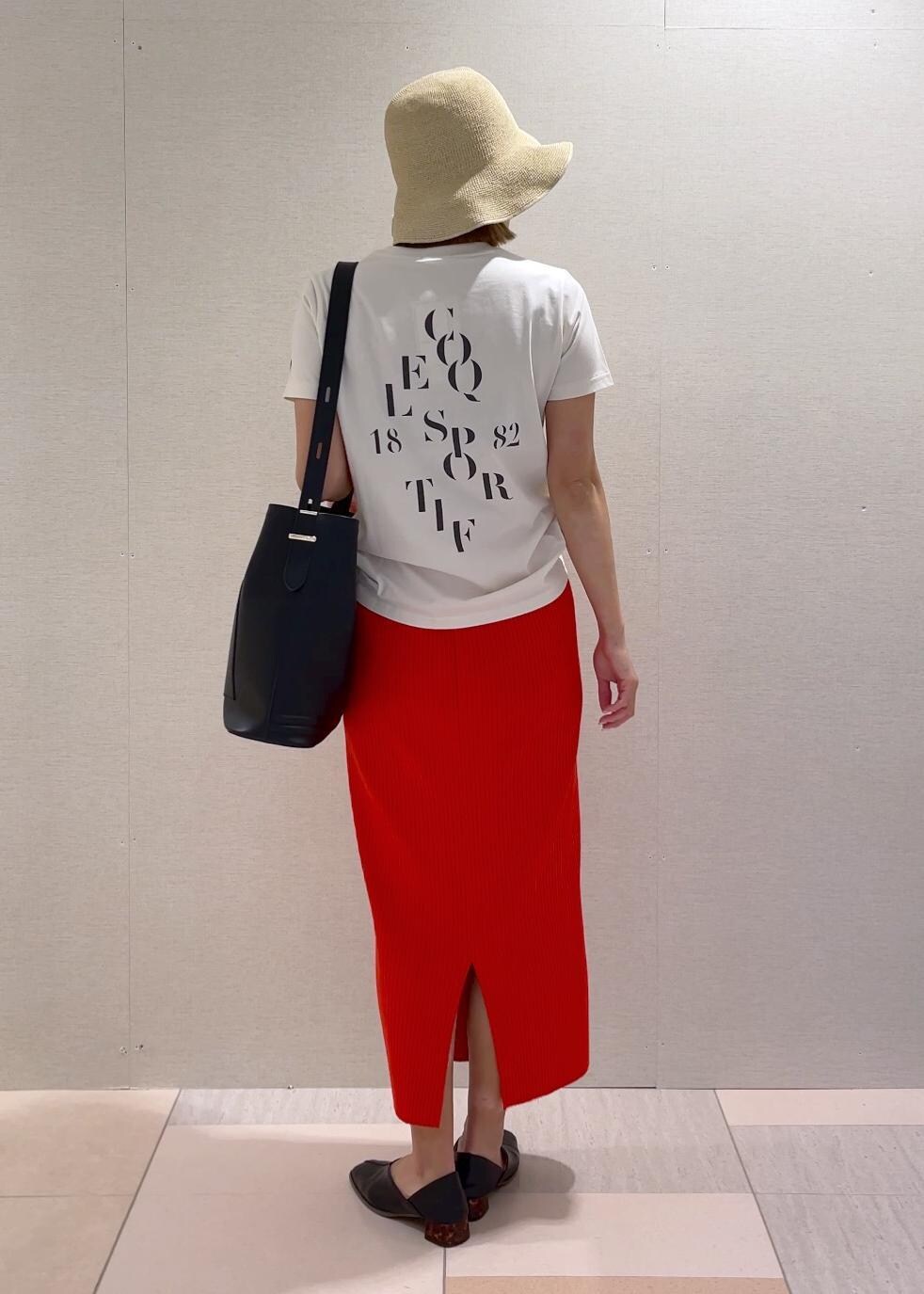 オレンジ系のスカート、ブラック系のトートバッグ、ブラック系のパンプスを着用したレディースの春コーディネートの5枚目の写真