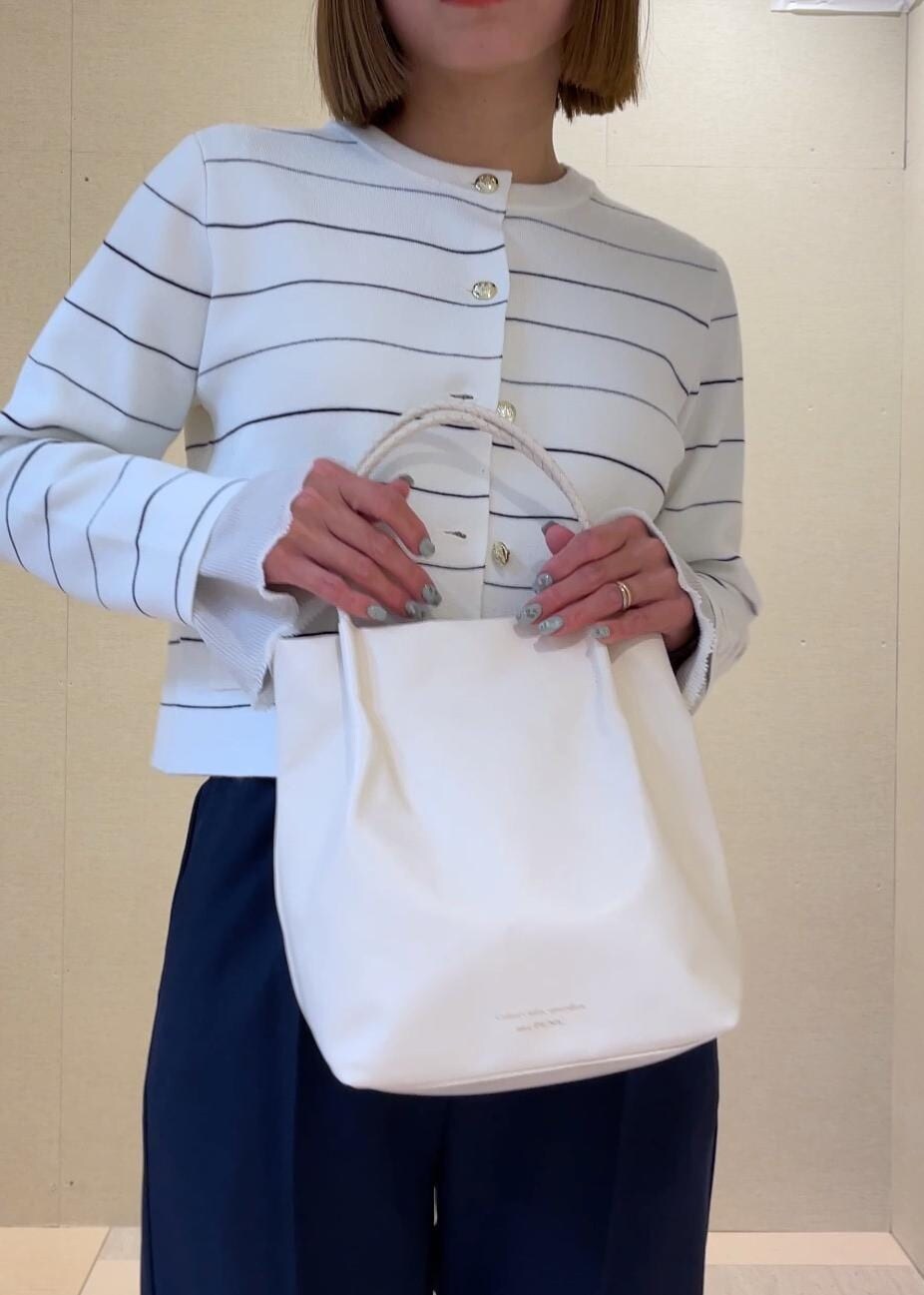 ホワイト系のトートバッグ、グレー系のニット/セーター、ホワイト系のカーディガン/ボレロを着用したレディースの冬コーディネートの6枚目の写真