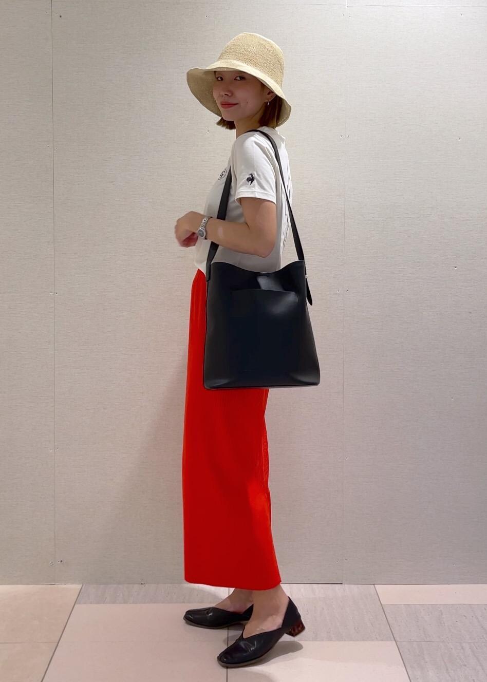 オレンジ系のスカート、ブラック系のトートバッグ、ブラック系のパンプスを着用したレディースの春コーディネートの2枚目の写真