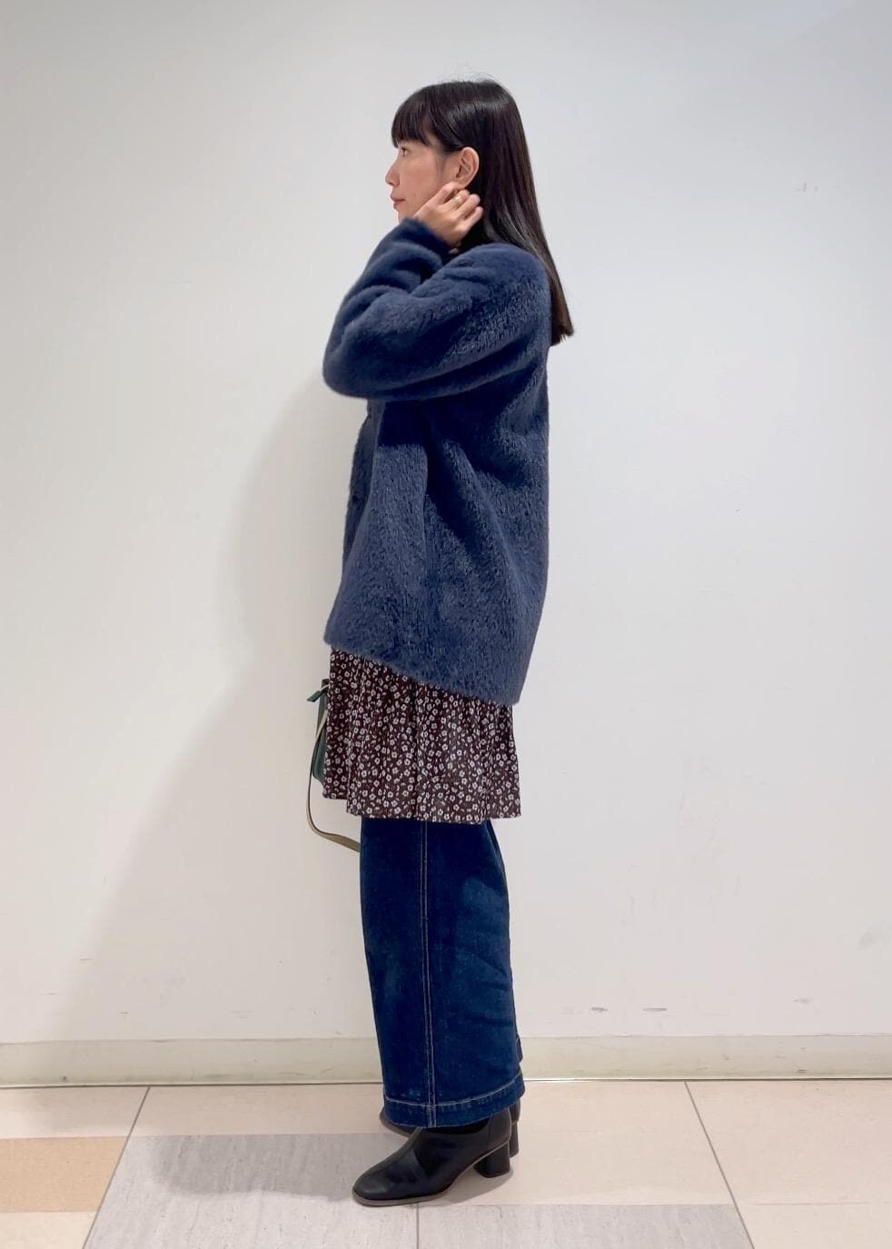 ブルー系のデニムパンツ、ブラウン系のワンピース、ブラック系のブーツを着用したレディースの冬コーディネートの2枚目の写真