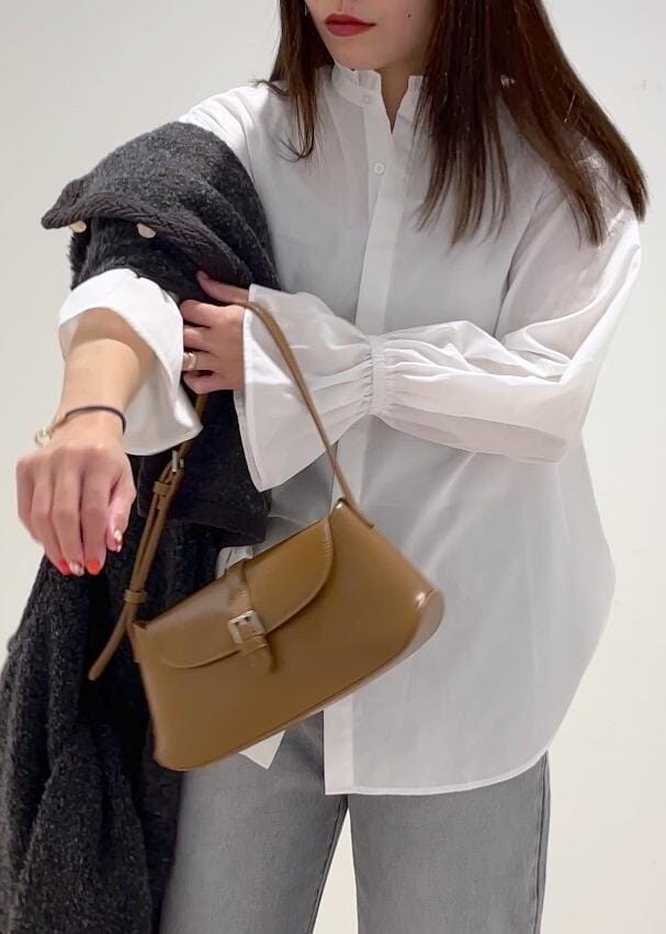 ブラウン系のショルダーバッグ、ブラック系のブーツ、グレー系のブルゾンを着用したレディースの冬コーディネートの7枚目の写真