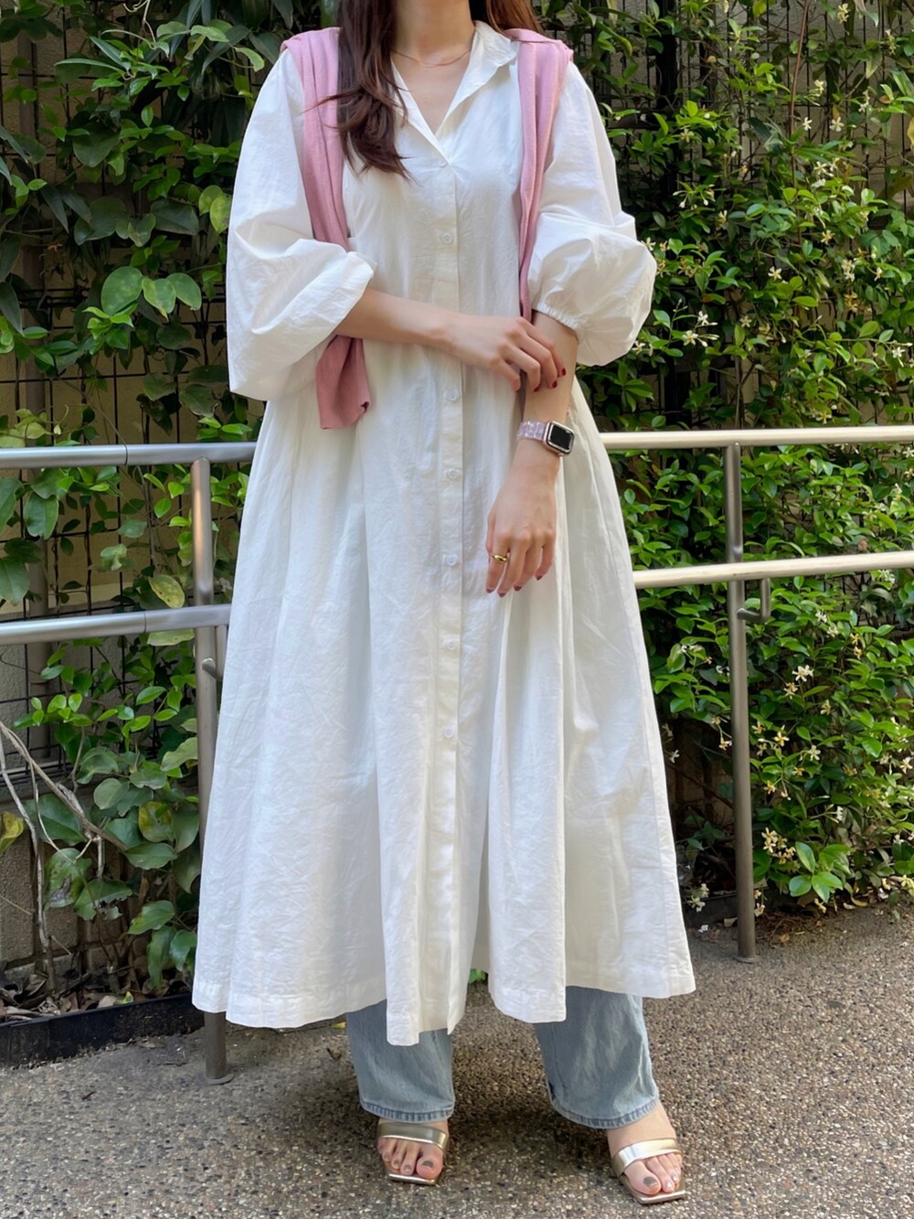 ホワイト系のシャツワンピース、ブルー系のデニムパンツ、ゴールド系のシューズを着用したレディースの春コーディネートの2枚目の写真