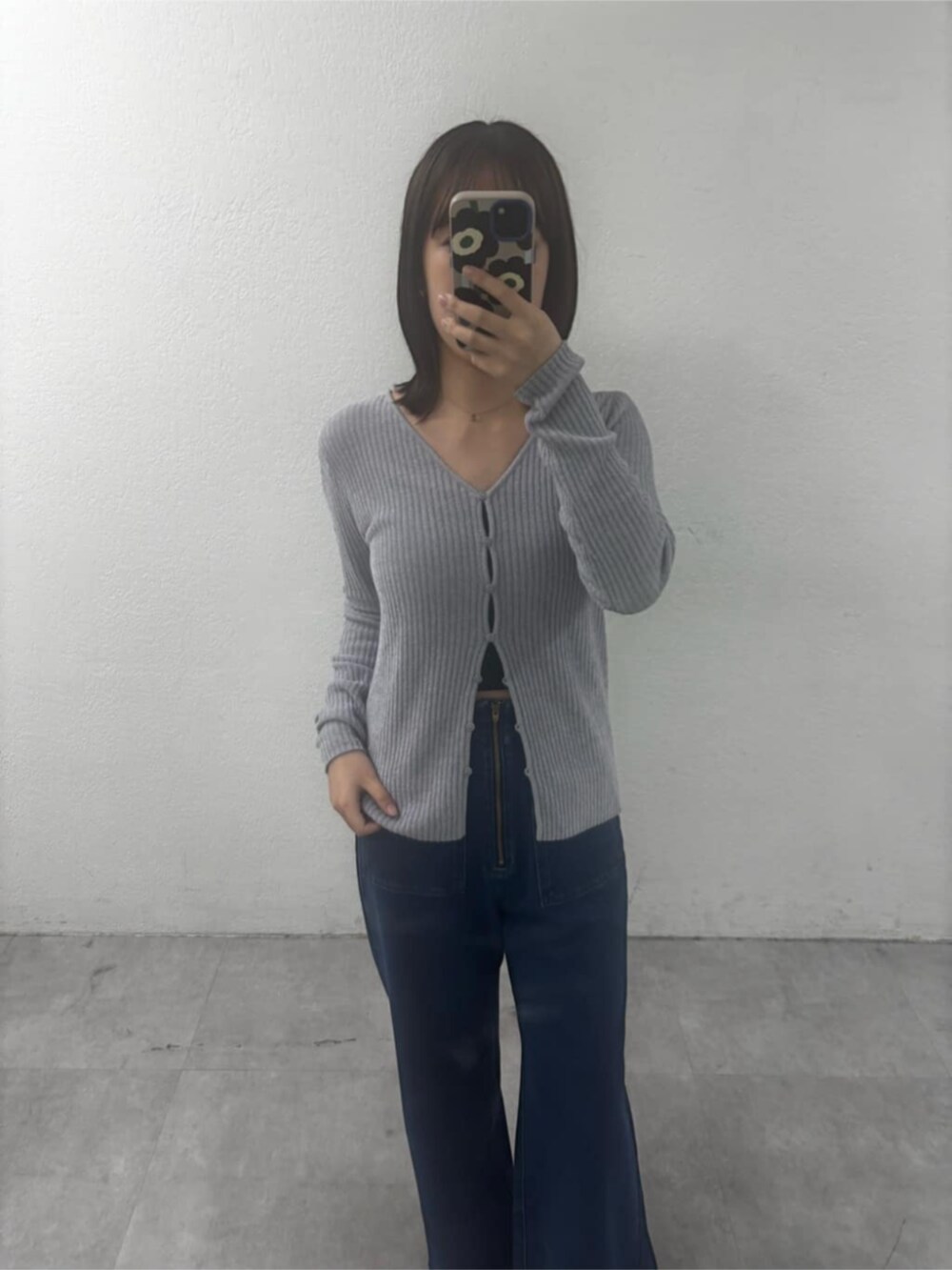 レッド系のスニーカー、グレー系のカーディガン/ボレロ、ブルー系のデニムパンツを着用したレディースの秋コーディネートの2枚目の写真