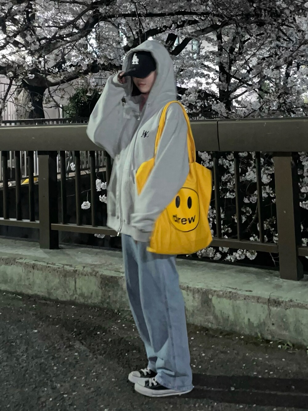 イエロー系のトートバッグ、グレー系のパーカー、ブラック系のスニーカーを着用したレディースの春コーディネートの2枚目の写真