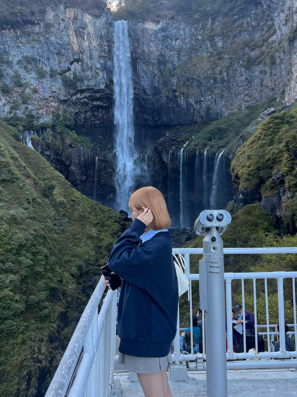 ブルー系のスウェット、グレー系のスカート、ホワイト系のスニーカーを着用したレディースの秋コーディネートの2枚目の写真