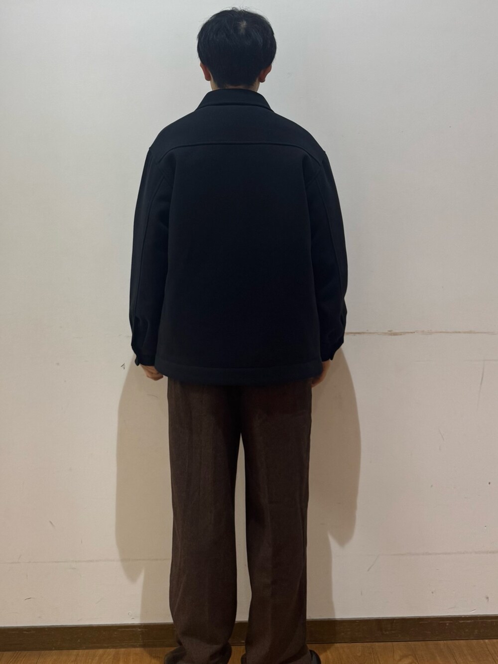 ホワイト系のニット/セーター、ブラウン系のその他パンツ、ブラック系のダウンジャケット/コートを着用したメンズの冬コーディネートの3枚目の写真